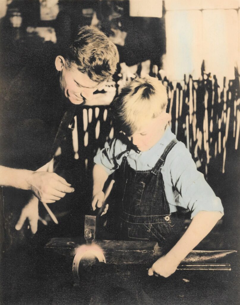 blacksmith teaching son to fit a horseshoe at anvil